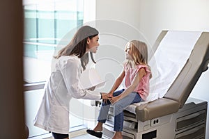 Pediatrician In White Coat With Child In Exam Room photo