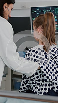 Pediatrician woman doctor examining sick patient using medical stethoscope