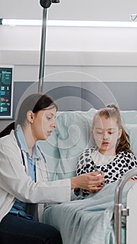 Pediatrician woman doctor putting medical oximeter on little child patient finger