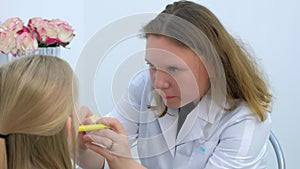 Pediatrician woman looking child girl sore throat using spatula and lantern.