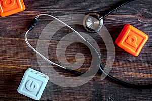 Pediatrician workplace with stethoscope and toys on wooden background top view