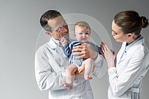 pediatricians trying to calm down little crying baby photo