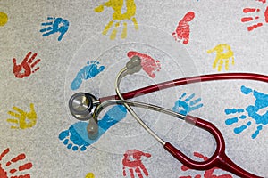 Pediatrics red Stethoscope on examination paper with imprint hands and feet images. child doctor. health concept.