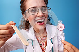 Pediatrist doctor with lollipop using spatula to examine throat