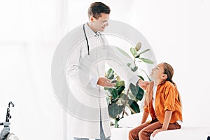 Pediatrist in white coat and child looking at each other in clinic