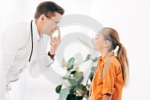 Pediatrist in white coat and child looking at each other in clinic