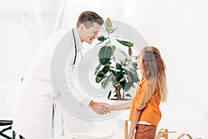 Pediatrist in white coat and child shaking hands