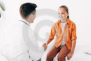 Pediatrist in white coat and child shaking hands