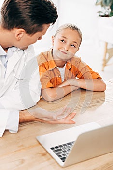 Pediatrist in white coat and child using laptop