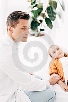 Pediatrist in white coat examining child