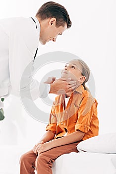 Pediatrist in white coat examining child in clinic