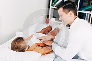 Pediatrist in white coat examining child in clinic