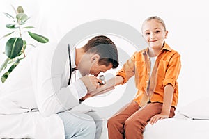 Pediatrist in white coat examining child with dermascope