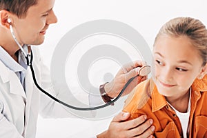 Pediatrist in white coat examining kid with stethoscope