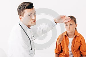 Pediatrist in white coat taking temperature of child