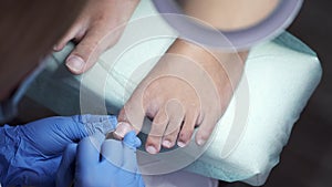 The pedicure master is polishing nails in a salon