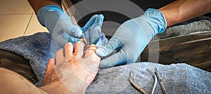 Pedicure - person with blue plastic gloves cuts client's toenails