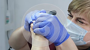 Pedicure SPA procedure in the beauty salon. Peeling feet. Electric apparatus for pedicure. Close up, selective focus.