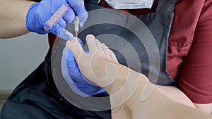 Pedicure SPA procedure in the beauty salon. Peeling feet. Electric apparatus for pedicure. Close up, selective focus.