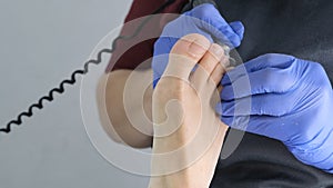 Pedicure SPA procedure in the beauty salon. Peeling feet. Electric apparatus for pedicure. Close up, selective focus.