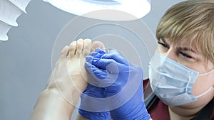 Pedicure SPA procedure in the beauty salon. Peeling feet. Electric apparatus for pedicure. Close up, selective focus.