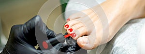 Pedicurist applying red nail polish