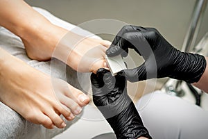 Pedicurist buffing toenail of woman