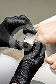 Pedicurist buffing toenail of woman