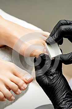 Pedicurist buffing toenail of woman