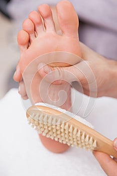 Pedicurist cleaning a customers foot