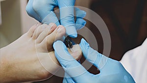 Pedicurist cuts cuticle on toe with nail tongs makes pedicure in beauty salon.