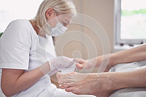 Pedicurist doing professional medical pedicure procedure in beauty salon with special eguipment. Foot treatment in SPA salon.