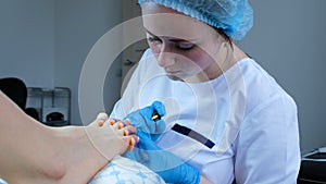 A pedicurist gently gel-polishes the toenails and places the UV lamp on top of the foot