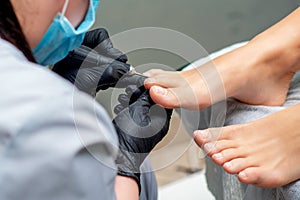 Pedicurist`s hands in gloves doing pedicure