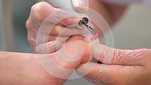 Pedicurist woman removes shellac polish from toes, apparatus hardware pedicure.