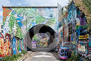 Pedley Street Arch, Shoreditch, East London. Pedestrian Alleyway under railway line near Brick Lane, covered in colourful graffiti