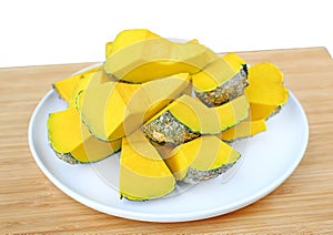 Peel and dissect pumpkin in white plate against wood background, cross section