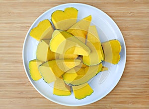 Peel and dissect pumpkin in white plate against wood background, cross section