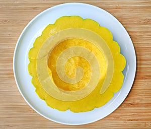 Peel and dissect pumpkin in white plate against wood background, cross section