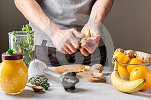 Peel ginger root from the shell. Clean food in the kitchen. Kitchen knife in hand