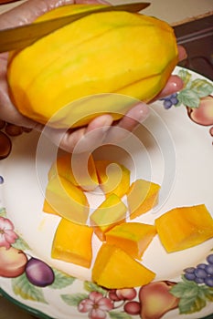 Peel the mango on a plate in the kitchen