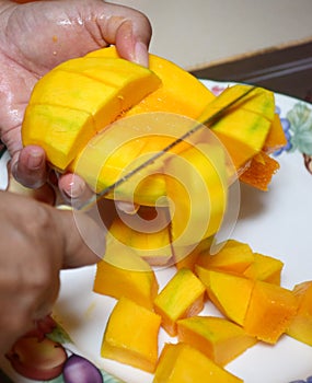 Peel the mango on a plate in the kitchen