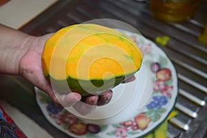 Peel the mango on a plate in the kitchen
