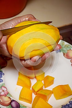 Peel the mango on a plate in the kitchen