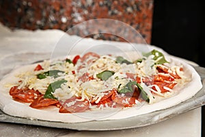 Peel with raw traditional Italian pizza on table in restaurant kitchen