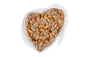 Peeled almonds in heart shaped plate isolated on white background. Healthy vegetarian snacks. Protein-containing food. Flat lay,