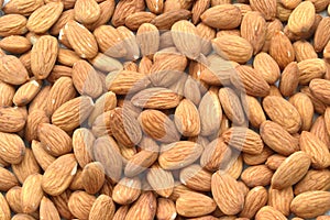 Peeled almonds are sprinkled on the table and make up a background of healthy plant products. Nuts, vegetable protein