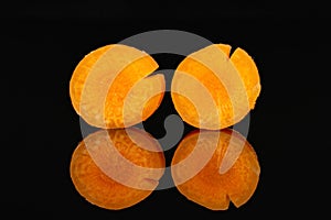 Peeled baby carrot isolated on black glass