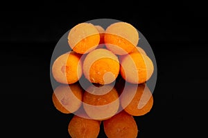 Peeled baby carrot isolated on black glass