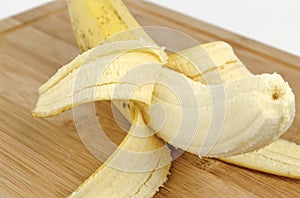 Peeled banana in Peel on a wooden cutting board